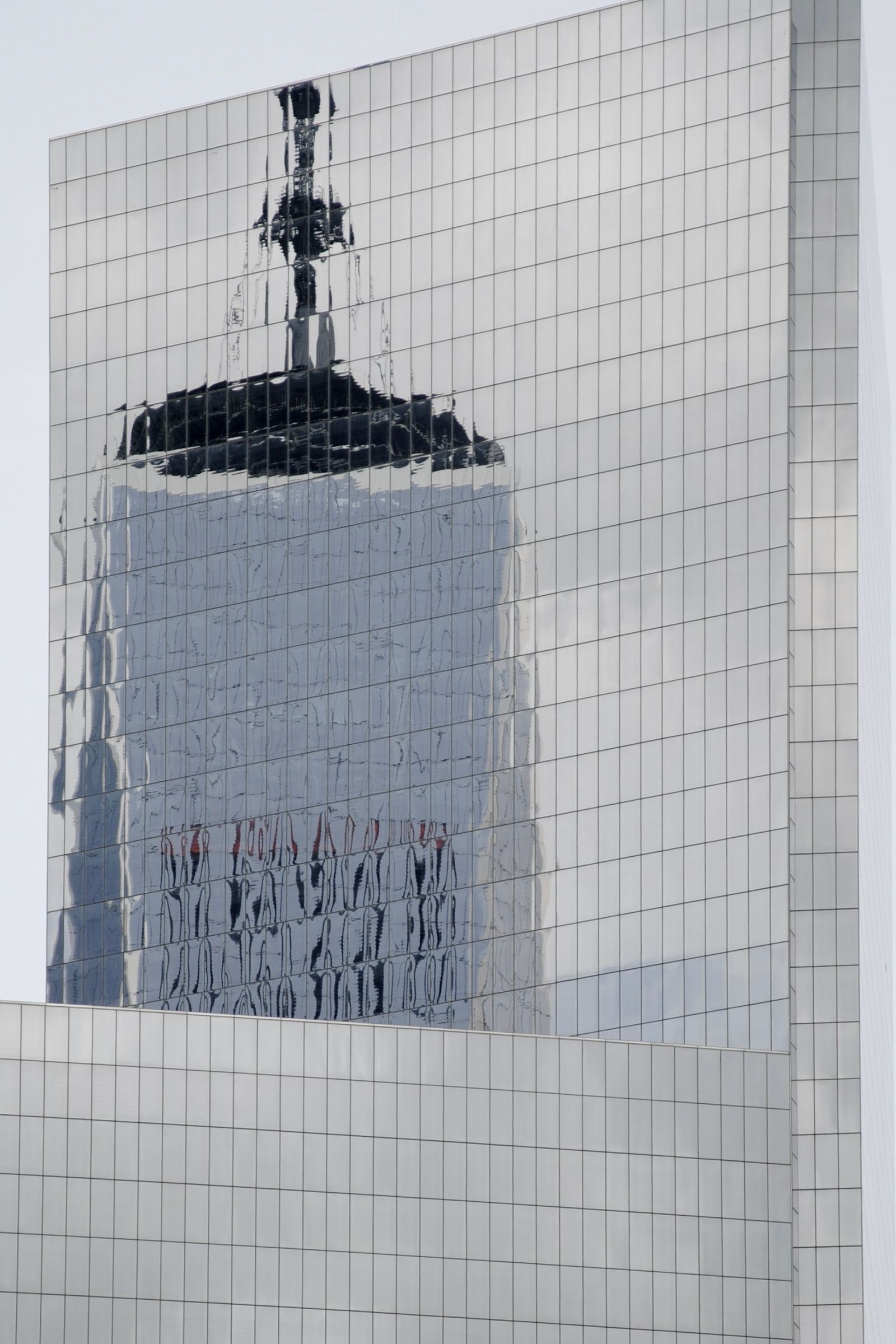 A skyscraper reflected across mirrored windows.