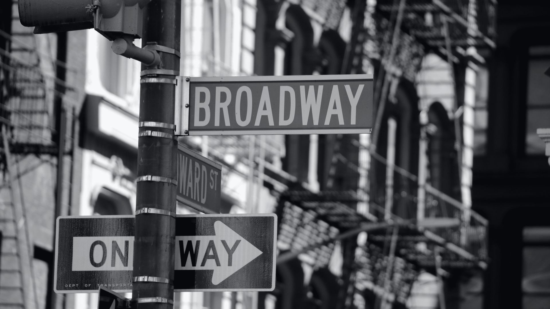 A Broadway street sign against cast-iron buildings.