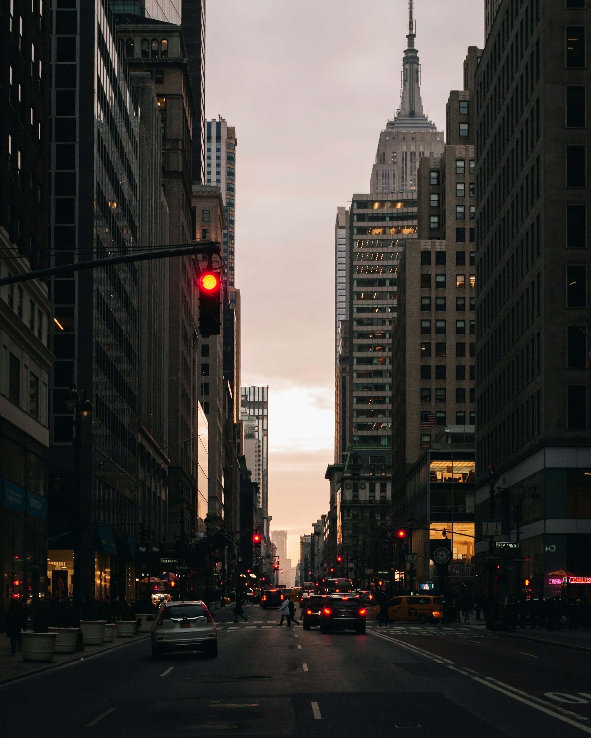 A Manhattan avenue at sunset, traffic moving.